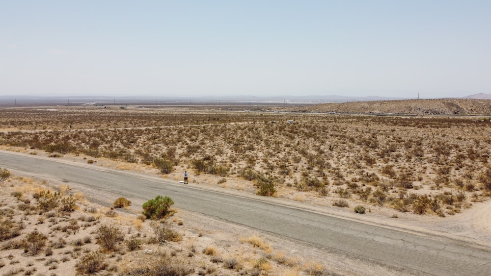 gray asphalt road in the middle of brown field during daytime