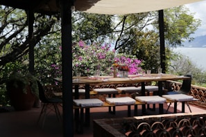 Outdoor dining area with wooden table and chairs under a pergola.