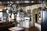 Compact kitchen with hanging pots and magnetic spice jars on the wall.