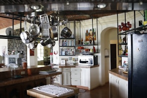 Compact kitchen with hanging pots and magnetic spice jars on the wall.