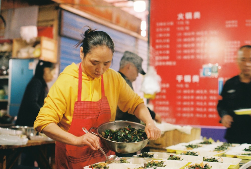 man in yellow and red apron holding black cooking pot