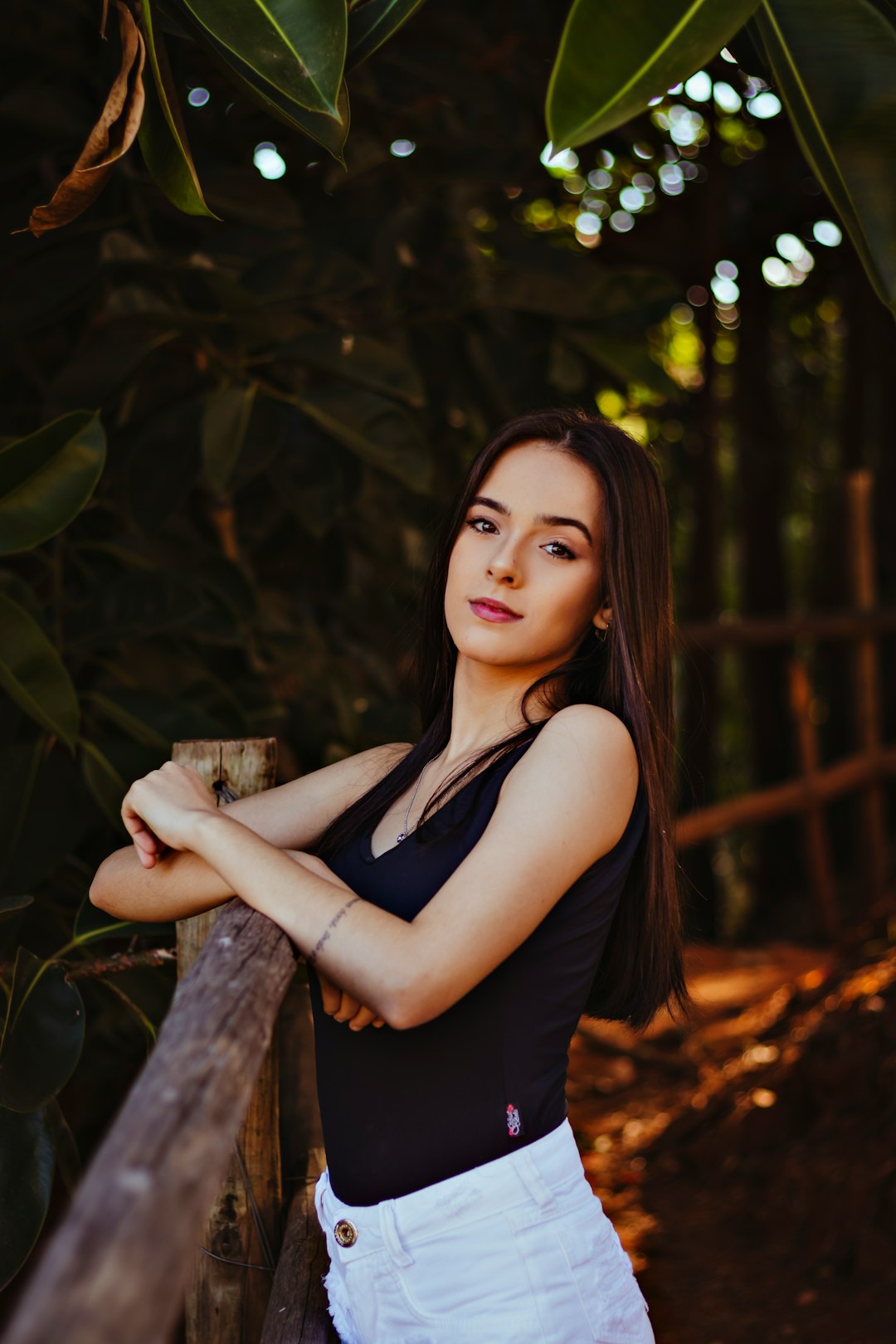 woman in black tank top leaning on brown tree