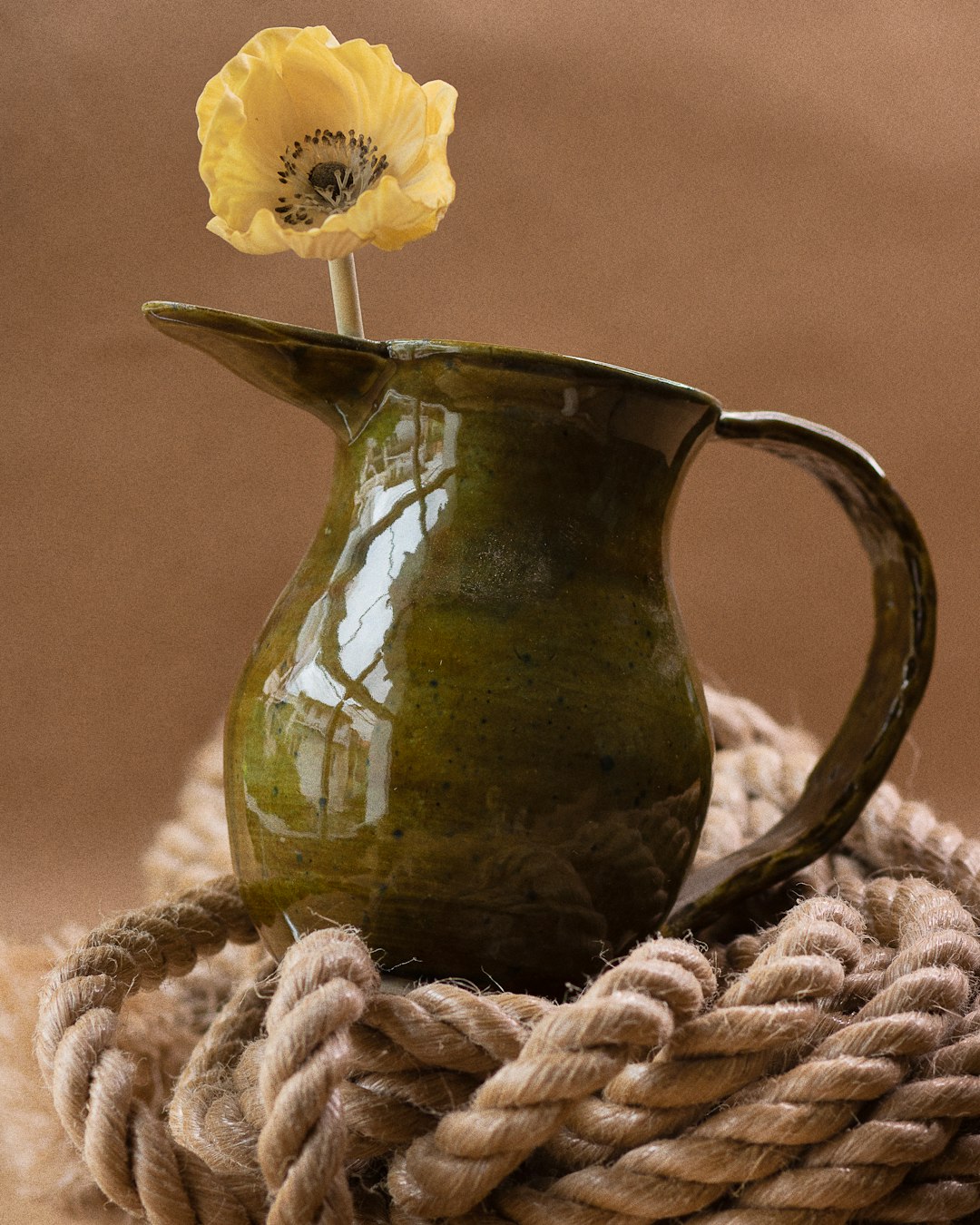 yellow flower in green ceramic vase