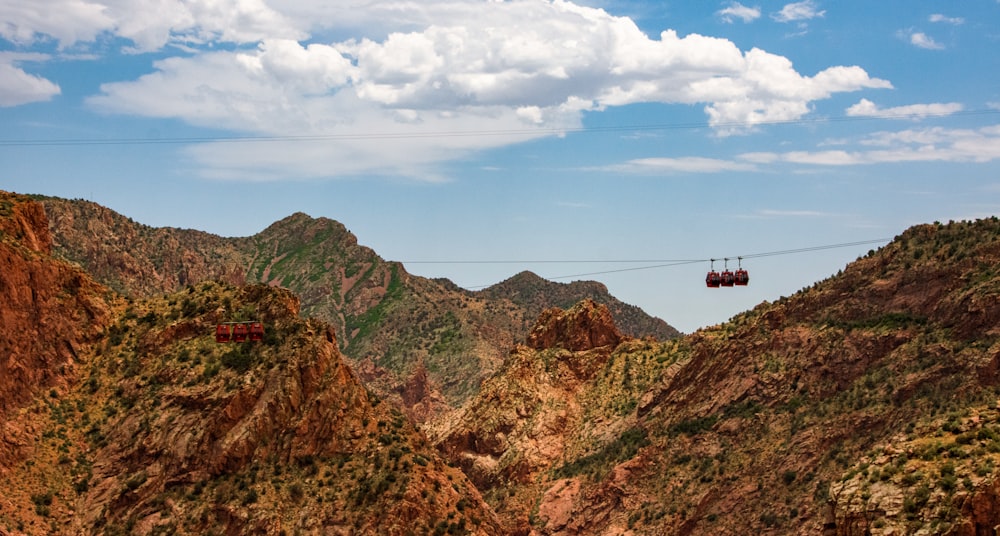 black cable car over brown and green mountain under blue and white cloudy sky during daytime