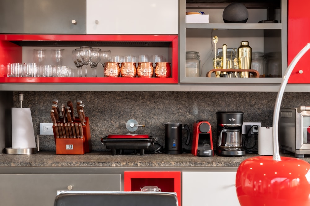 red and black coffee maker on white wooden shelf