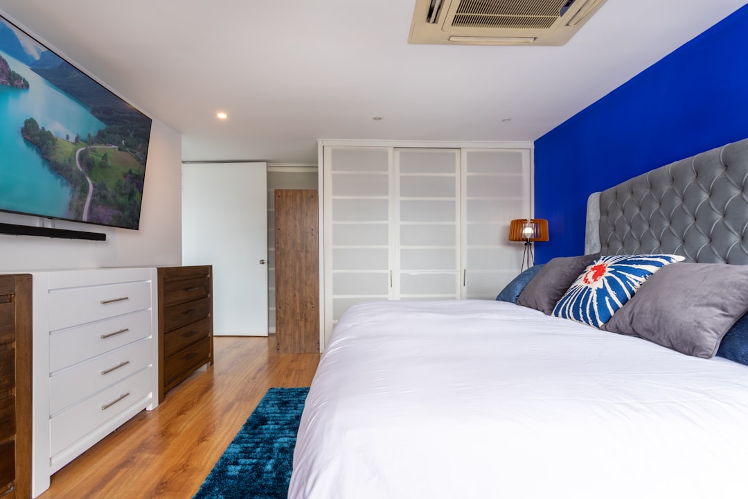 white bed linen near brown wooden cabinet