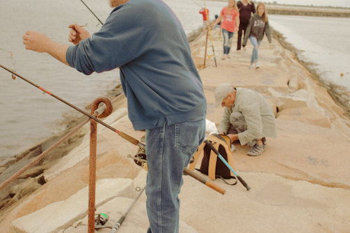 man in blue denim jeans and gray hoodie standing on brown wooden dock during daytime