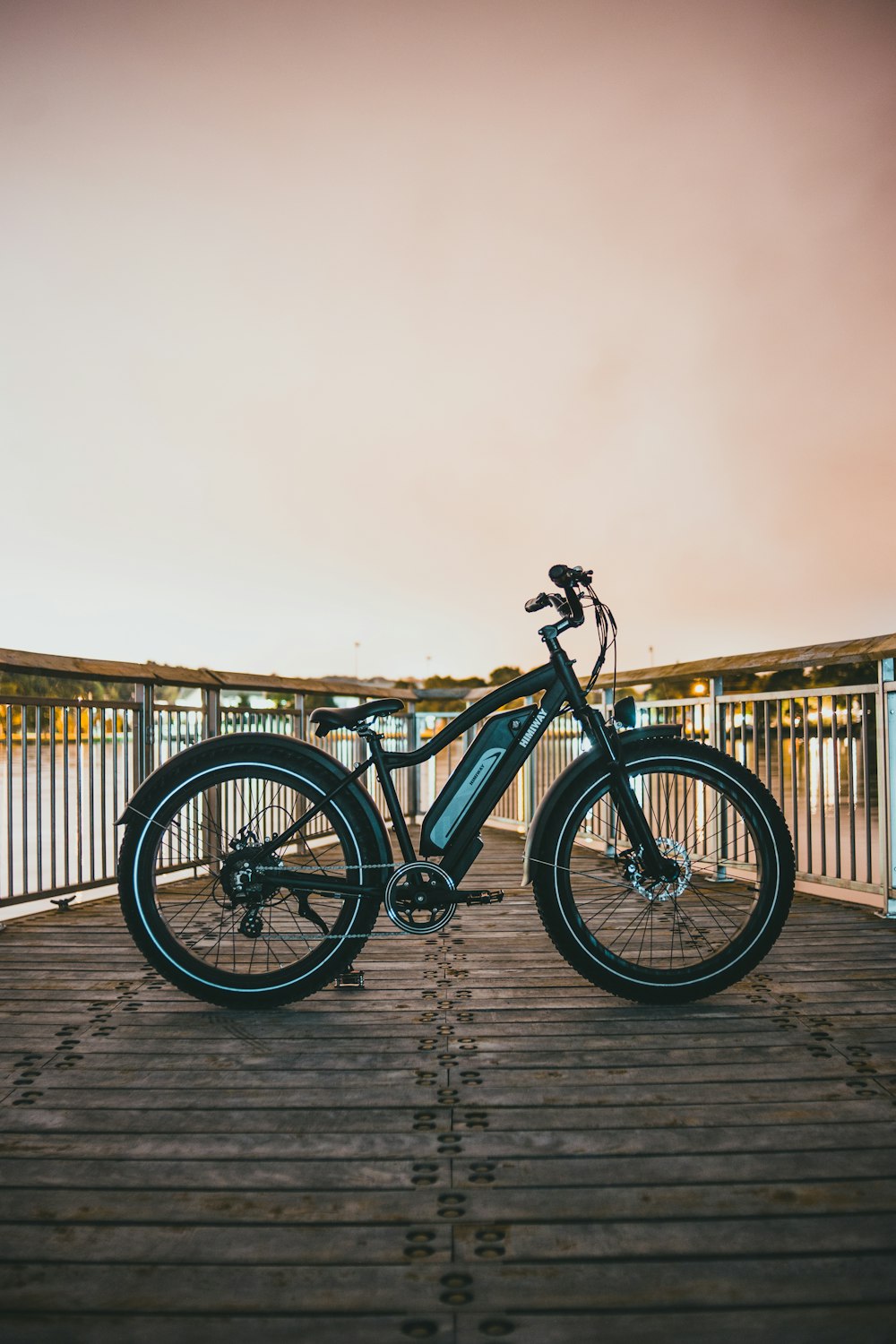 Bicicleta de montaña rígida negra y azul sobre muelle de madera marrón durante el día