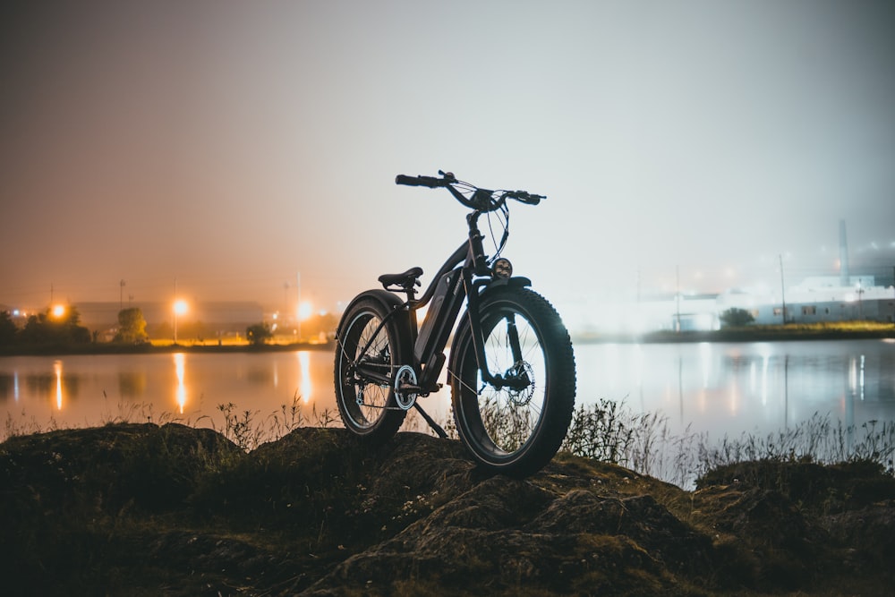 black and gray mountain bike near body of water during sunset
