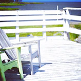 A rustic outdoor chair with visible wood grain placed on a wooden deck.