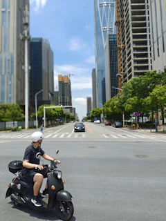 A rider wearing a helmet cruising through an urban street with skyscrapers in the background.