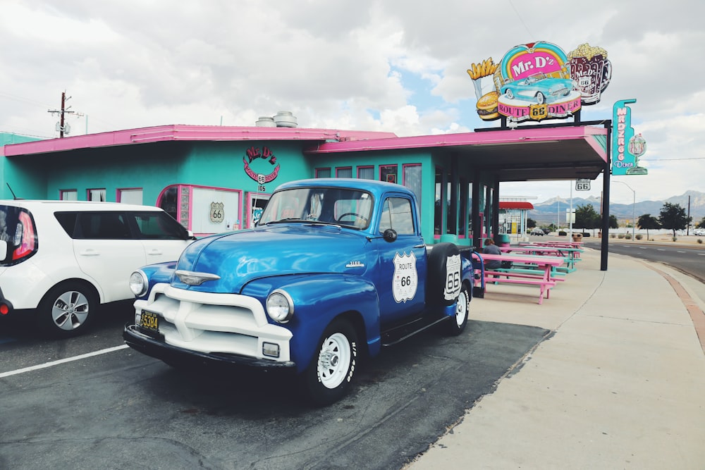 Voiture Chevrolet bleue et blanche garée à côté d’un mur bleu et rose