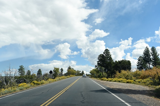 gray concrete road under white clouds and blue sky during daytime