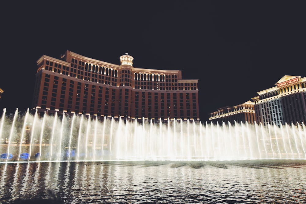 water fountain in front of brown building during nighttime