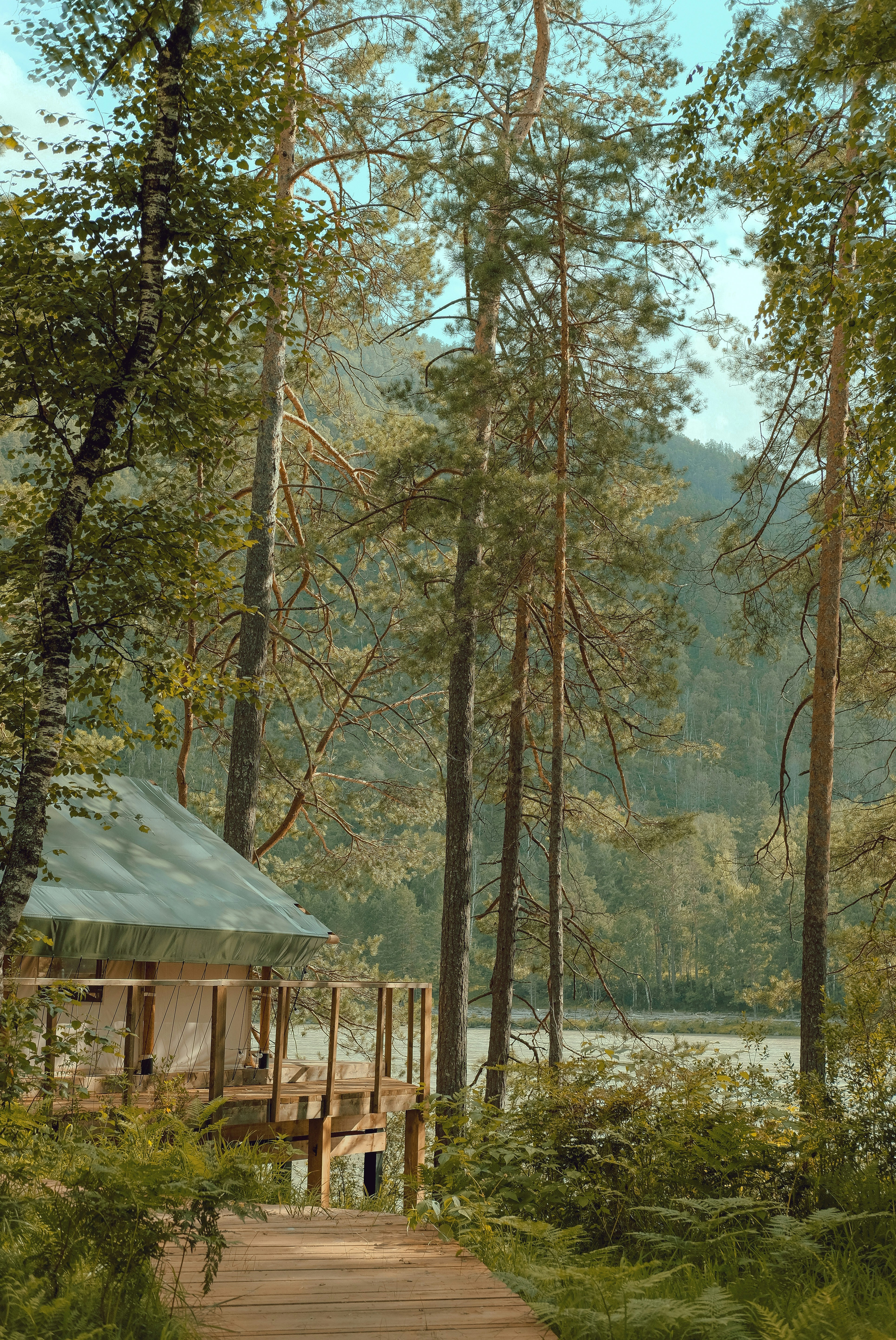 Luxury glamping tent on lakeside at dawn, soft morning mist, intimate and peaceful