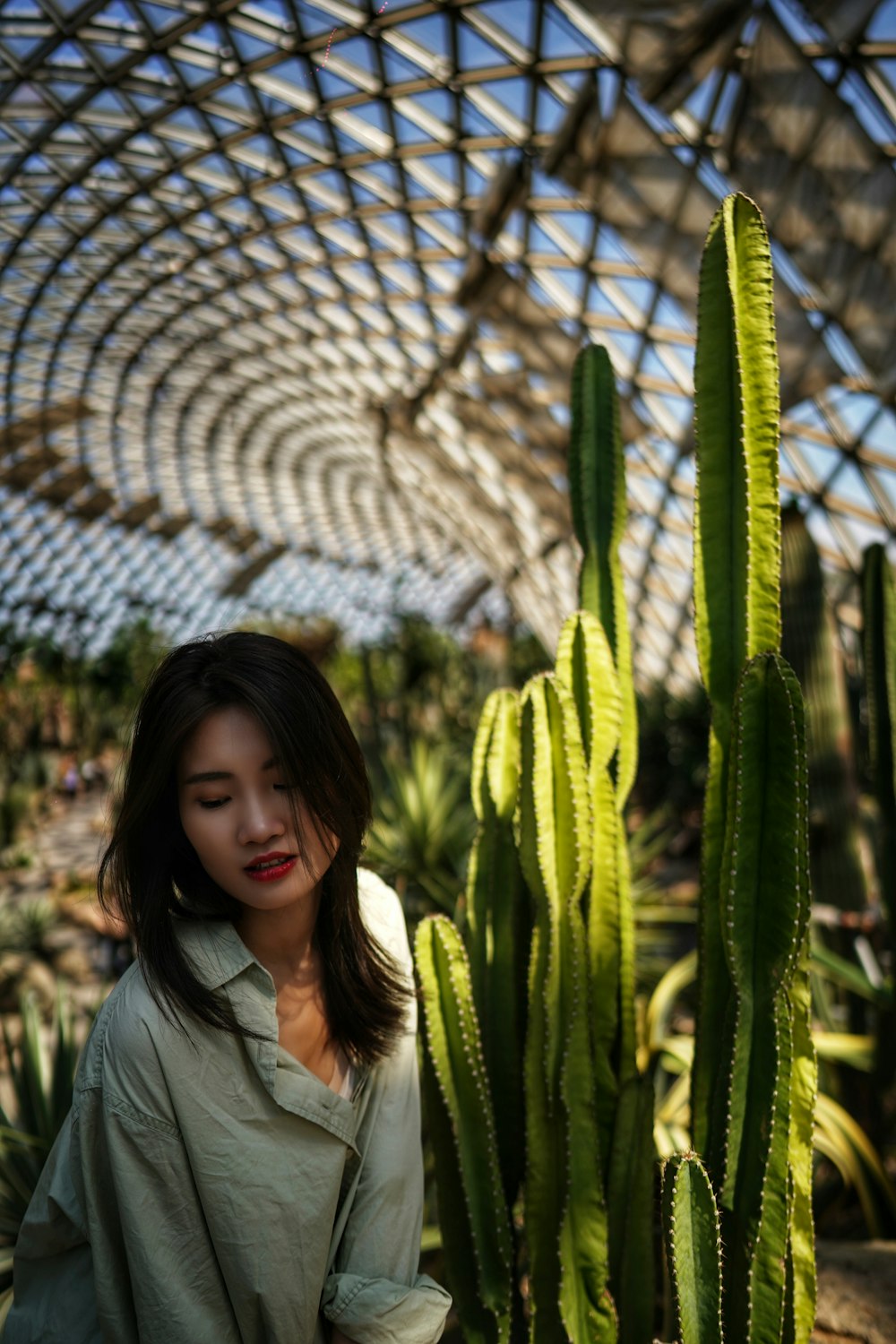 woman in gray jacket standing near green plant