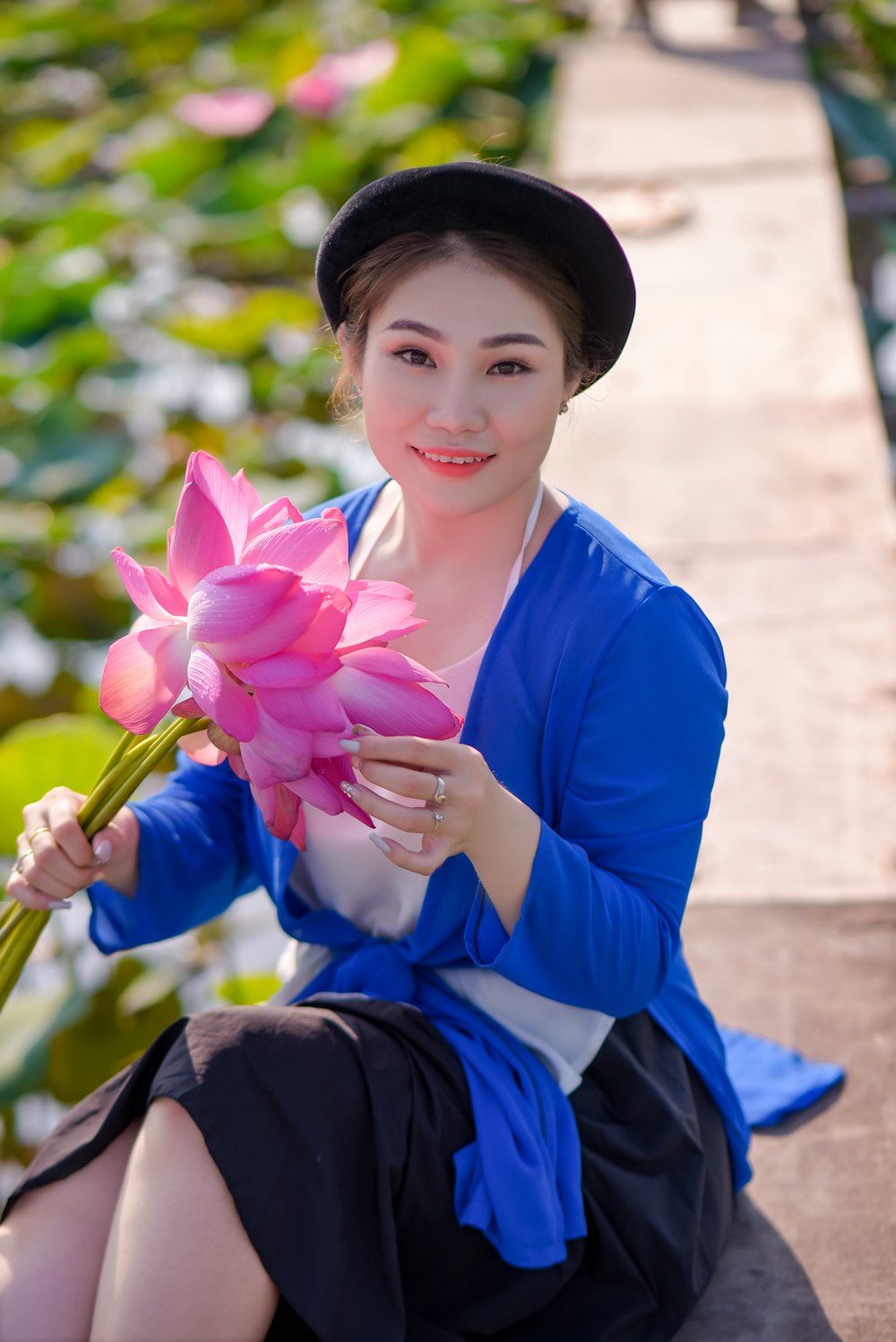 woman in blue long sleeve shirt holding pink flower