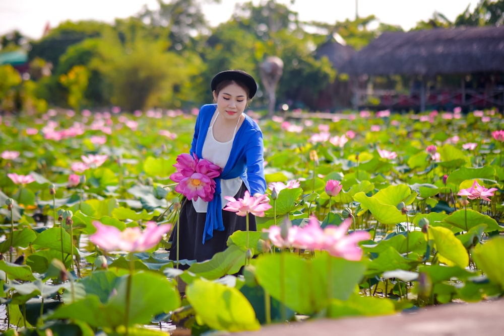 girl in blue and white school uniform holding purple flower during daytime