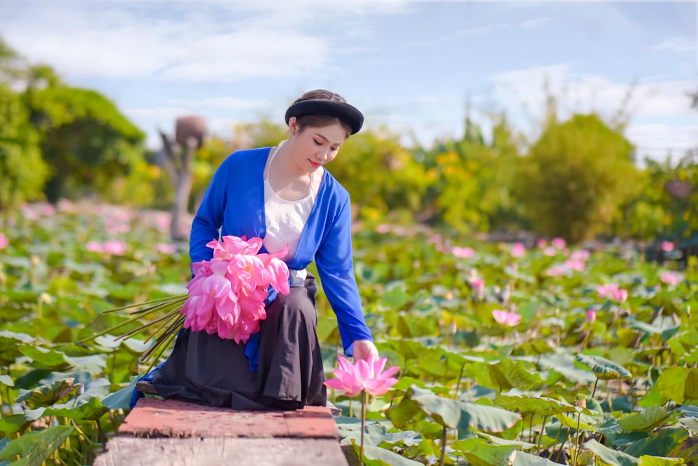 girl in blue long sleeve shirt holding pink flower bouquet