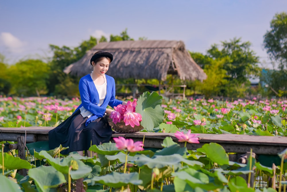 woman in blue long sleeve dress holding pink flower