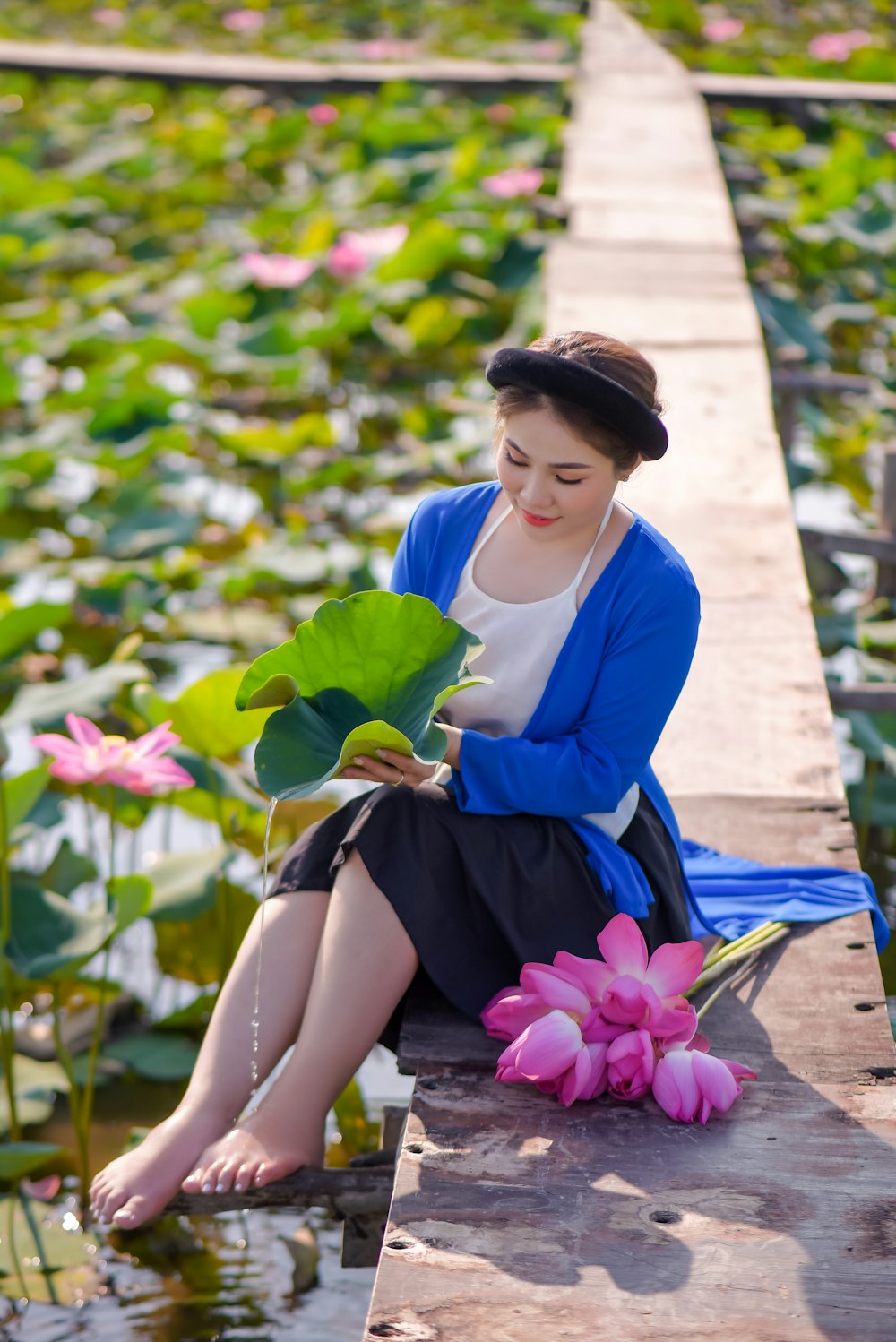 woman in blue and white long sleeve dress holding pink flower