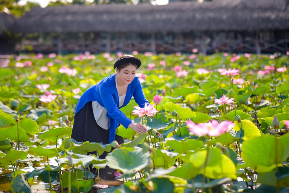 woman in blue long sleeve shirt and black skirt standing in front of purple flowers