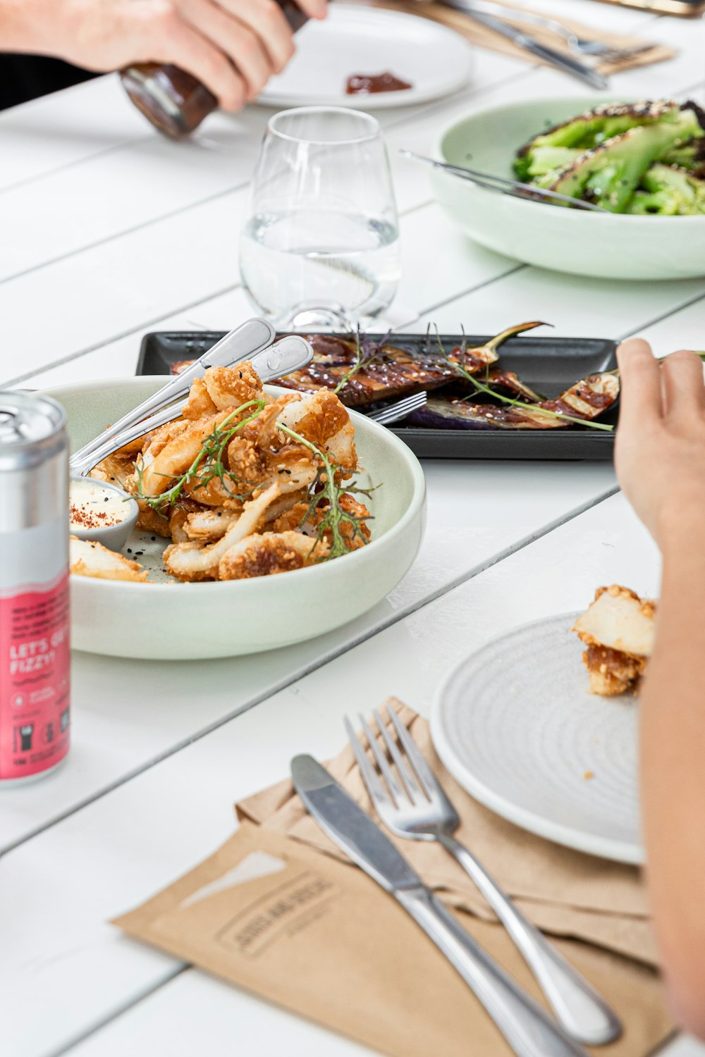 person holding fork and knife slicing food on white ceramic plate