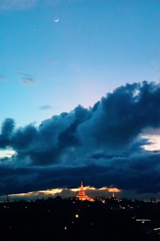 A serene night sky filled with twinkling stars and a glowing crescent moon over an ancient temple silhouette.