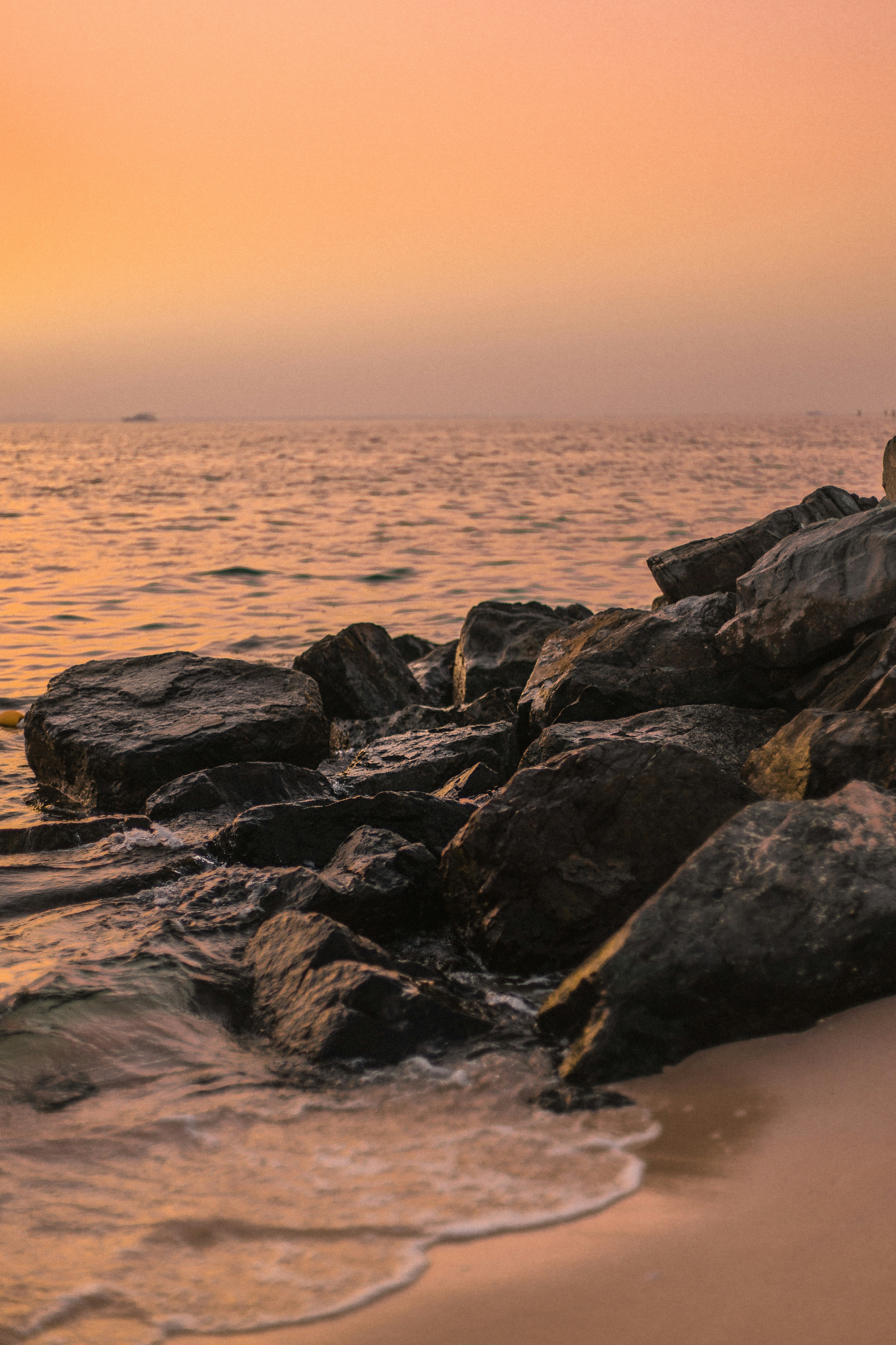 black and gray rocks on sea shore during sunset