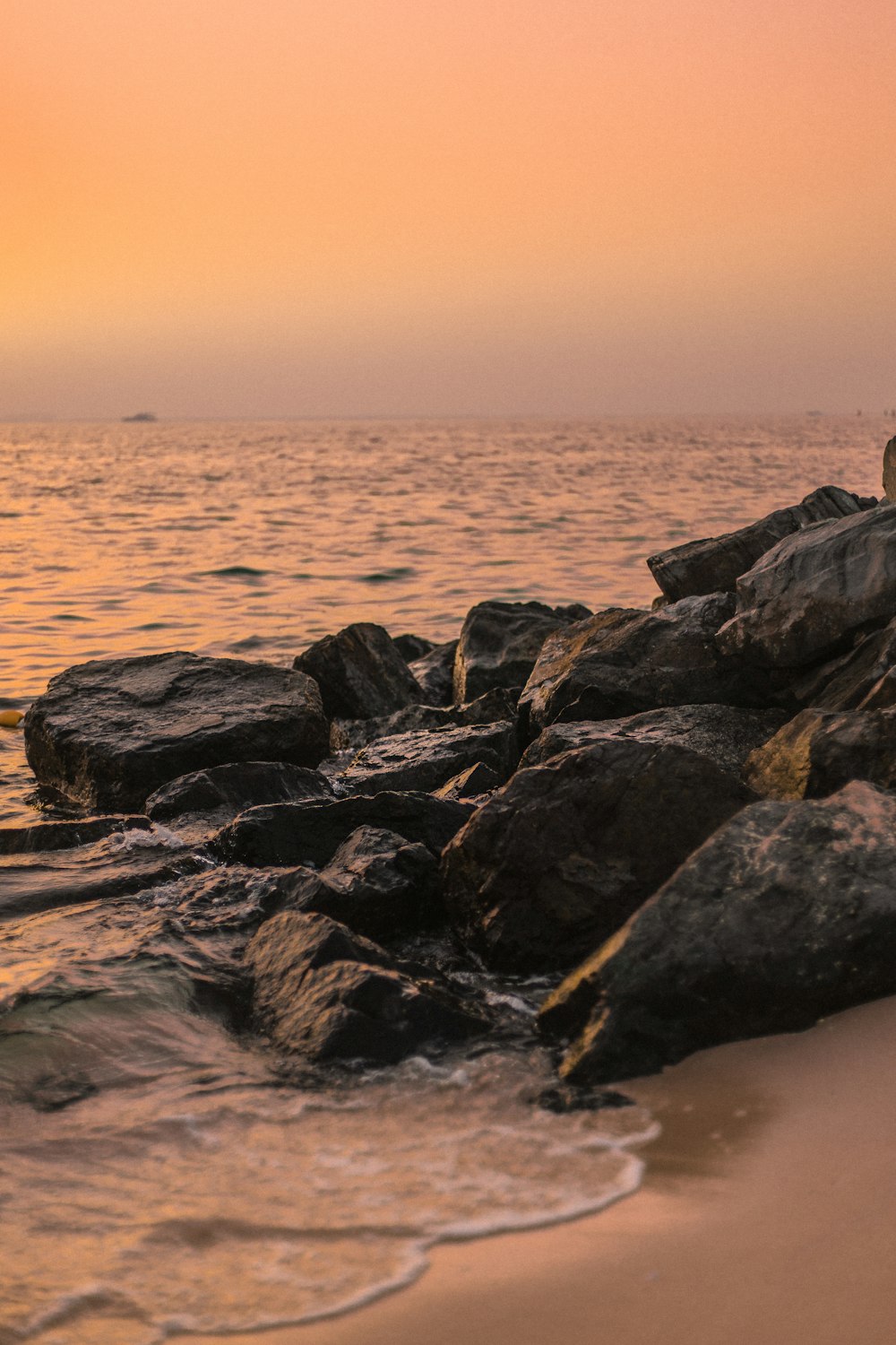 black and gray rocks on sea shore during sunset