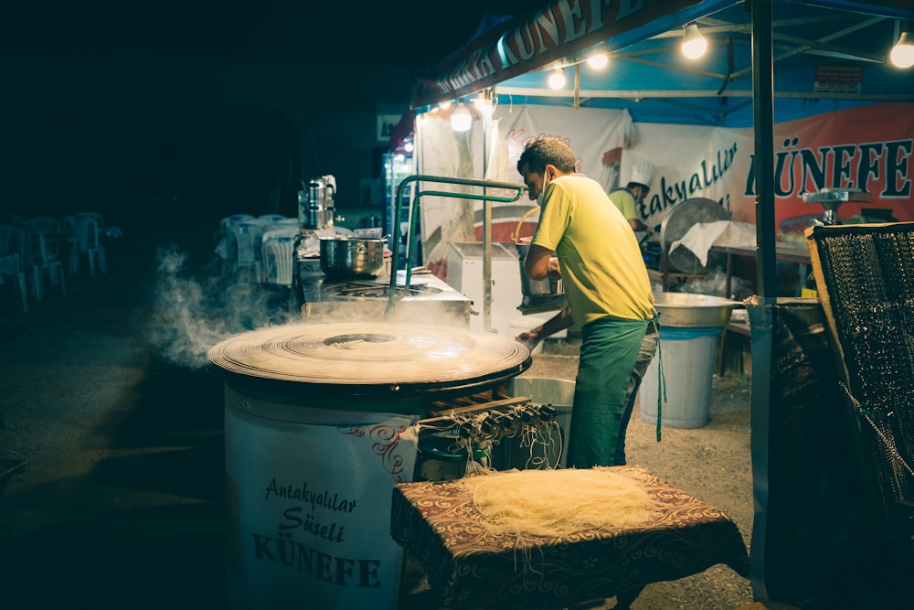 man in yellow polo shirt and green pants standing near white round table during nighttime