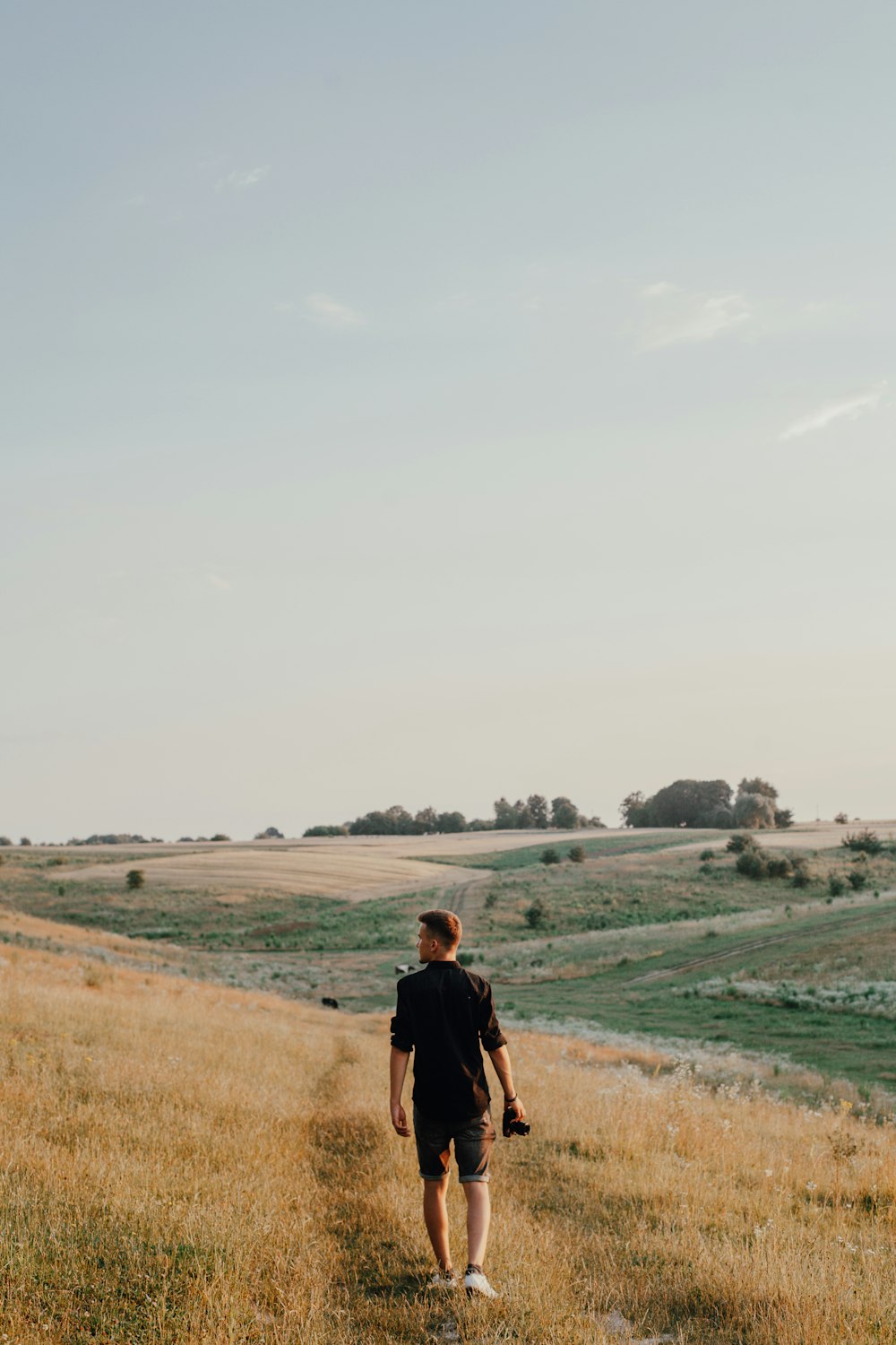 man in black jacket walking on green grass field during daytime