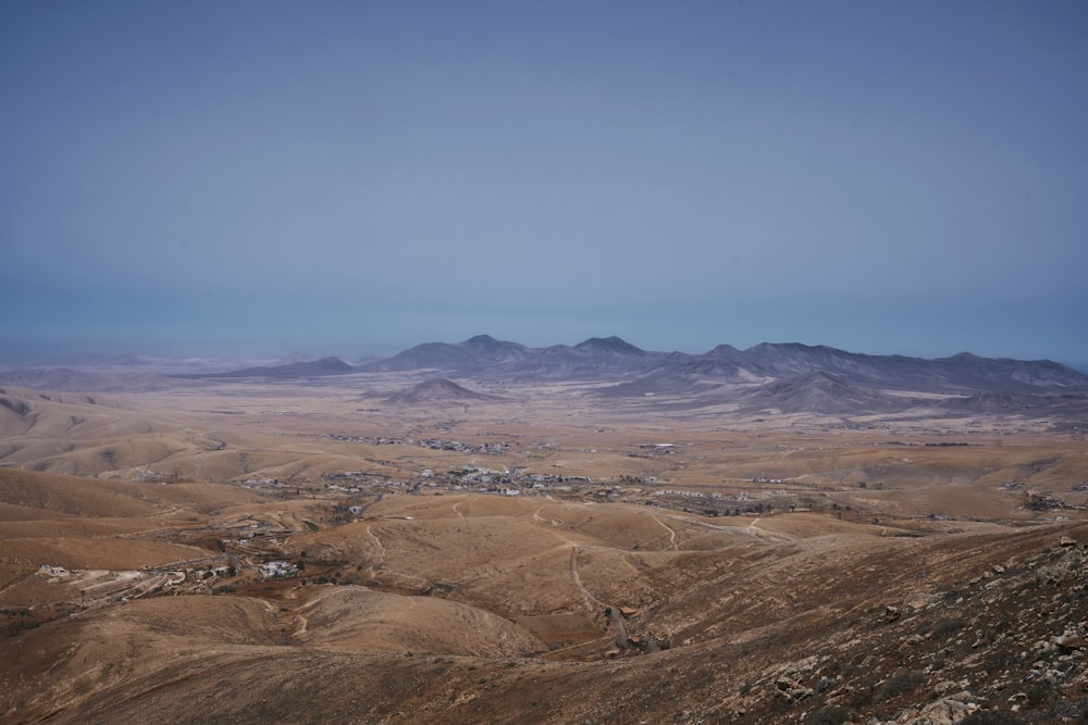 a view of a desert with mountains in the background