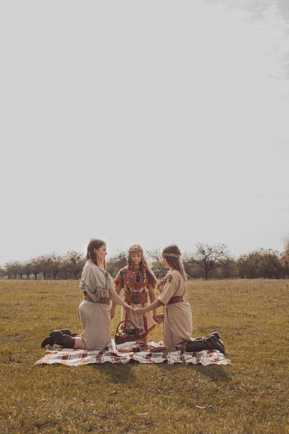 3 women sitting on brown wooden bench on green grass field during daytime