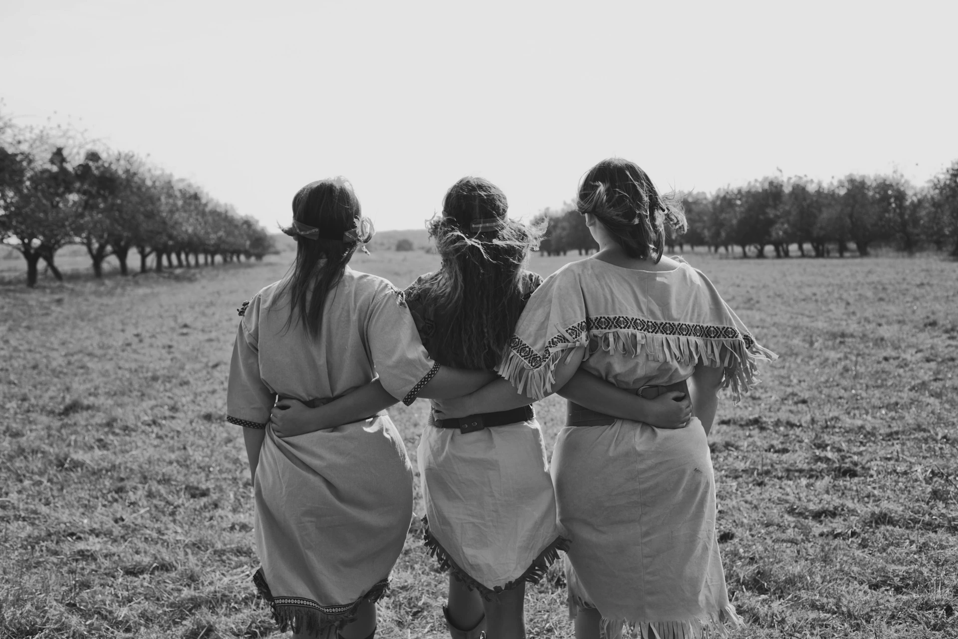 grayscale photo of 3 men standing on grass field