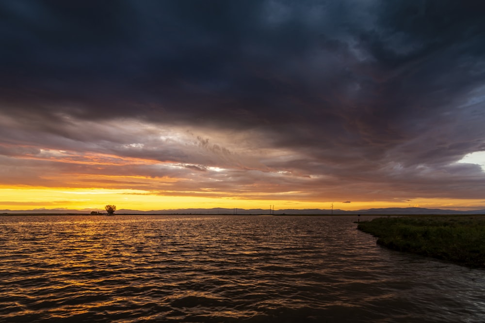 body of water under cloudy sky during sunset