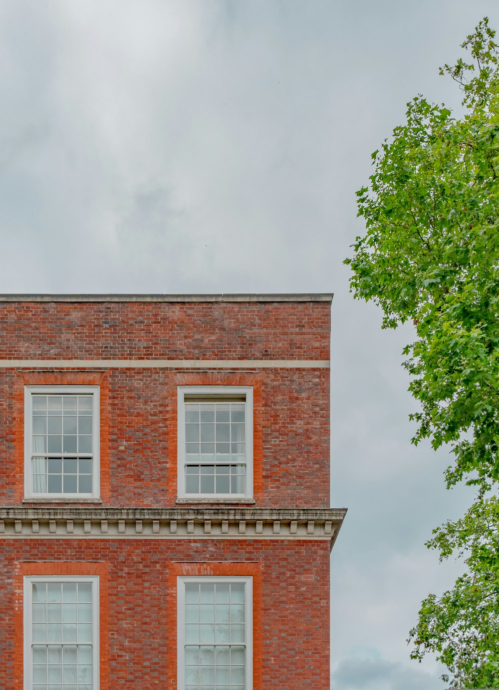 brown brick building near green tree during daytime