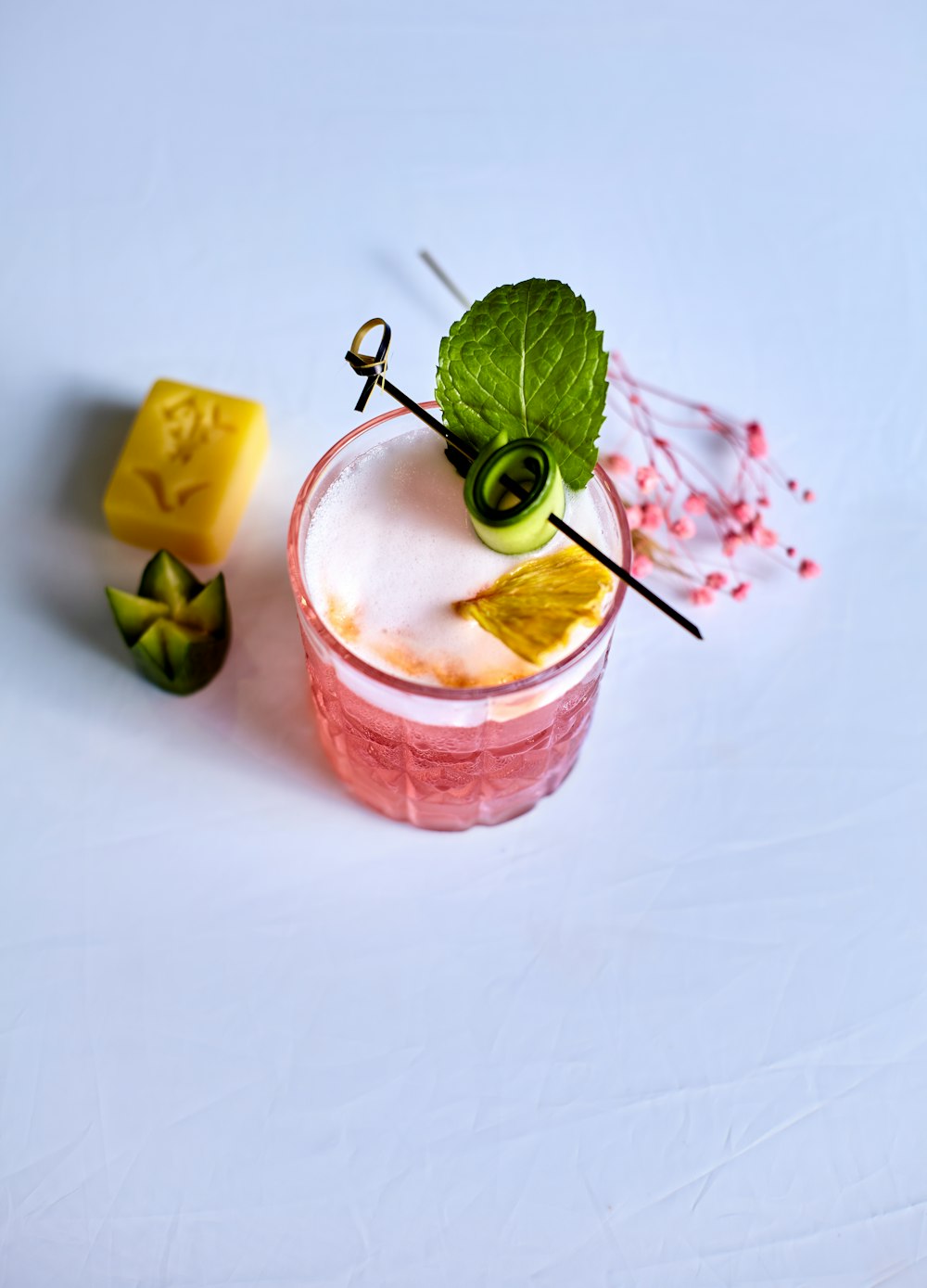 pink liquid in clear drinking glass with ice and green leaf