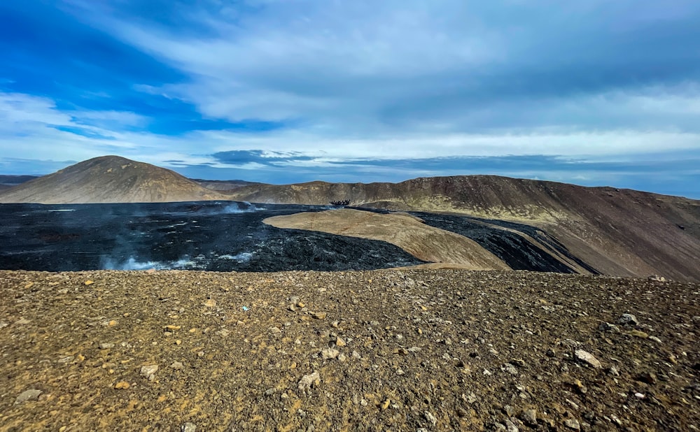 Montaña marrón cerca del cuerpo de agua bajo el cielo azul durante el día