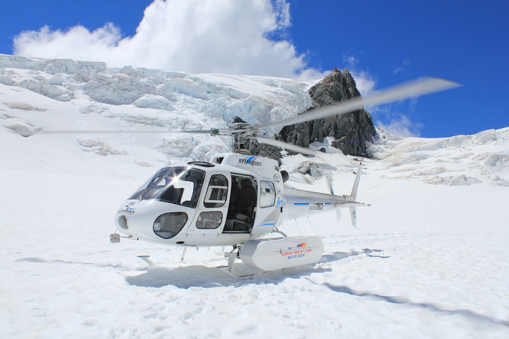 white and black helicopter on snow covered ground during daytime
