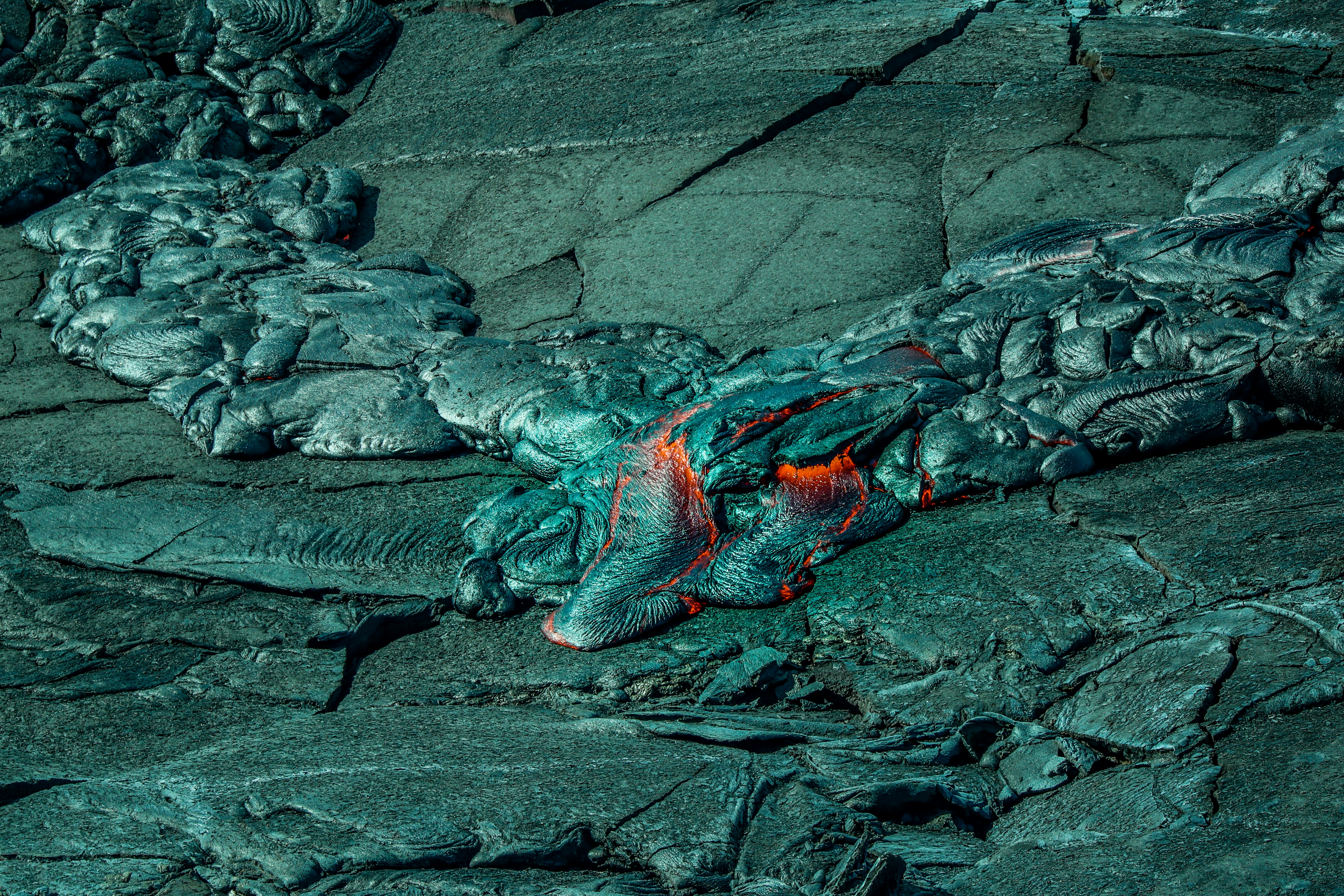 Glowing red lava flowing over dark volcanic rock with steam rising