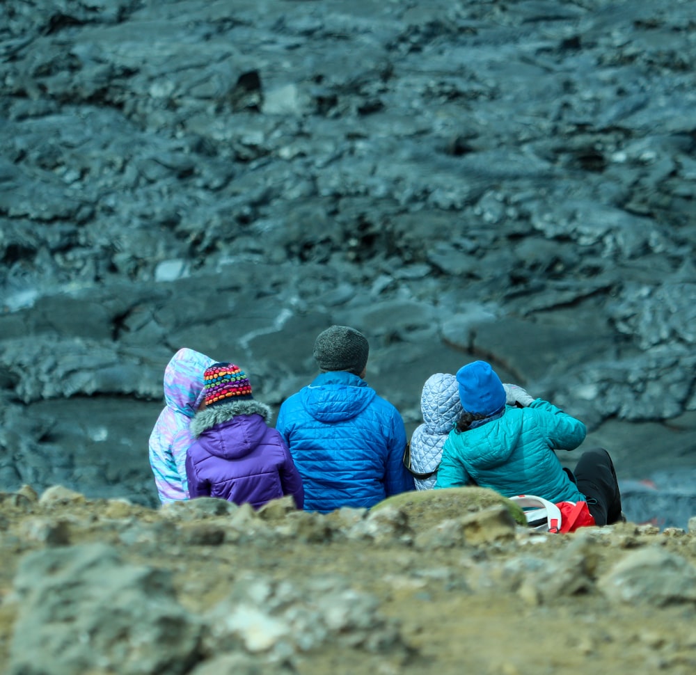 3 niños sentados en la roca marrón durante el día