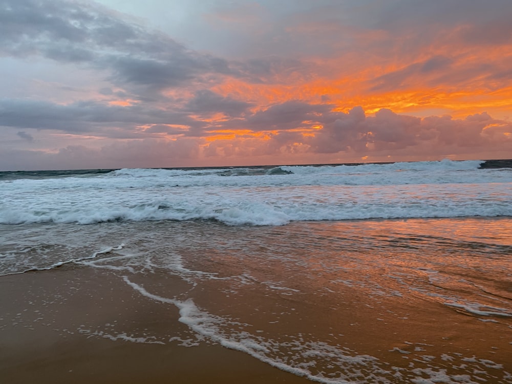 ocean waves crashing on shore during sunset