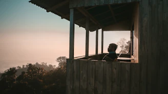 Tony seated on a weathered wooden porch, desert sunset painting the sky behind him.