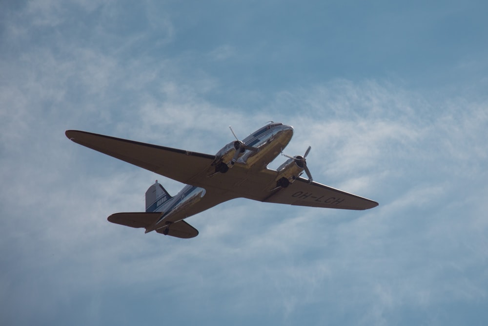 Braun-weißes Flugzeug, das tagsüber am Himmel fliegt