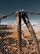 Operator installing a chain link fence post with the tractor’s attachments.
