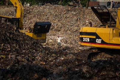 A commercial landscaping site showing workers loading debris into a large roll-off dumpster.