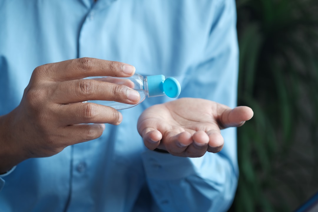 person holding blue plastic bottle, Using sanitizer liquid for preventing corona virus