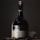 A bottle of St-Rémy Authentic French Brandy is set against a dark background. The bottle is elegantly designed with a black label featuring gold and red accents. The lighting highlights the curves and label details of the bottle, creating a sophisticated and classic appearance.
