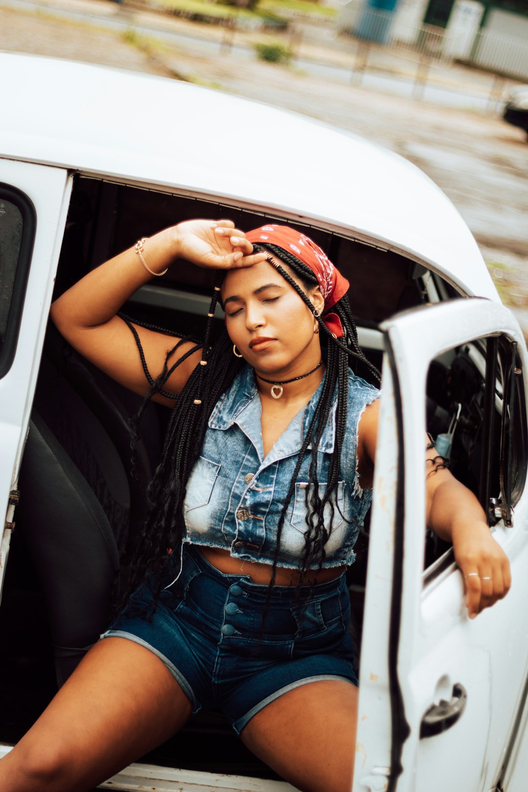 woman in blue denim vest sitting on car door during daytime